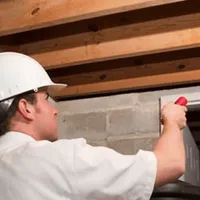 Termite inspection technician checking a basement wall and framing for termite activity in Fort Lauderdale, FL